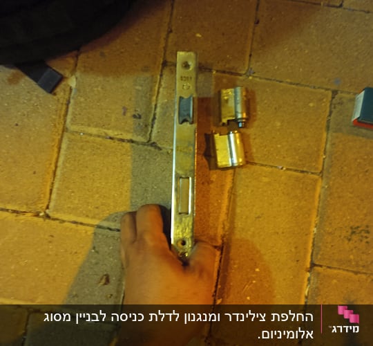 יד מחזיקה מנעול עם צילינדרים על רצפה מרוצפת